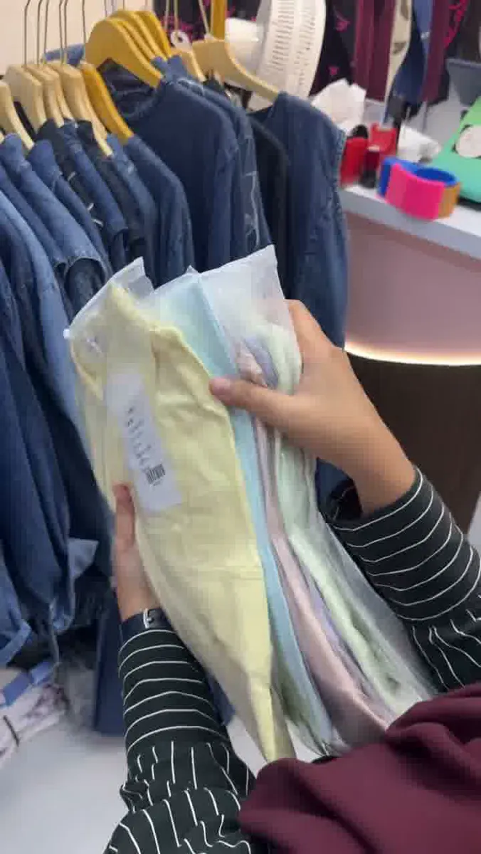 Tangan memilih pakaian warna pastel di toko grosir